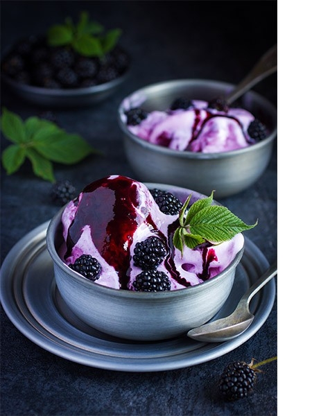 Zu sehen ist eine Schale mit Frozen Yogurt und Beeren. Daneben steht eine Schale mit Joghurt. Perfekt für den Sommer: Rezepte für selbstgemachtes Eis.