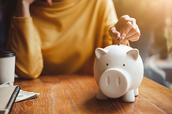 Eine Frau legt Geld in ihr Sparschwein - dank der REchnungskontrolle kann sie Geld einsparen