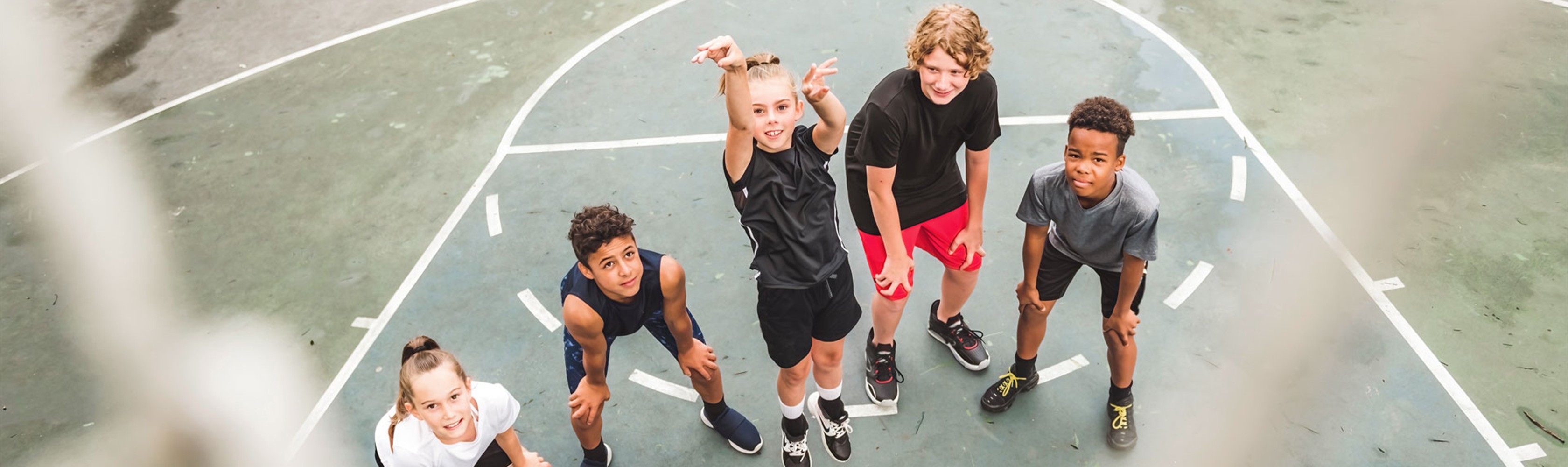 Kinder spielen auf dem Basketballplatz und träumen von einer Spitzensportkarriere.