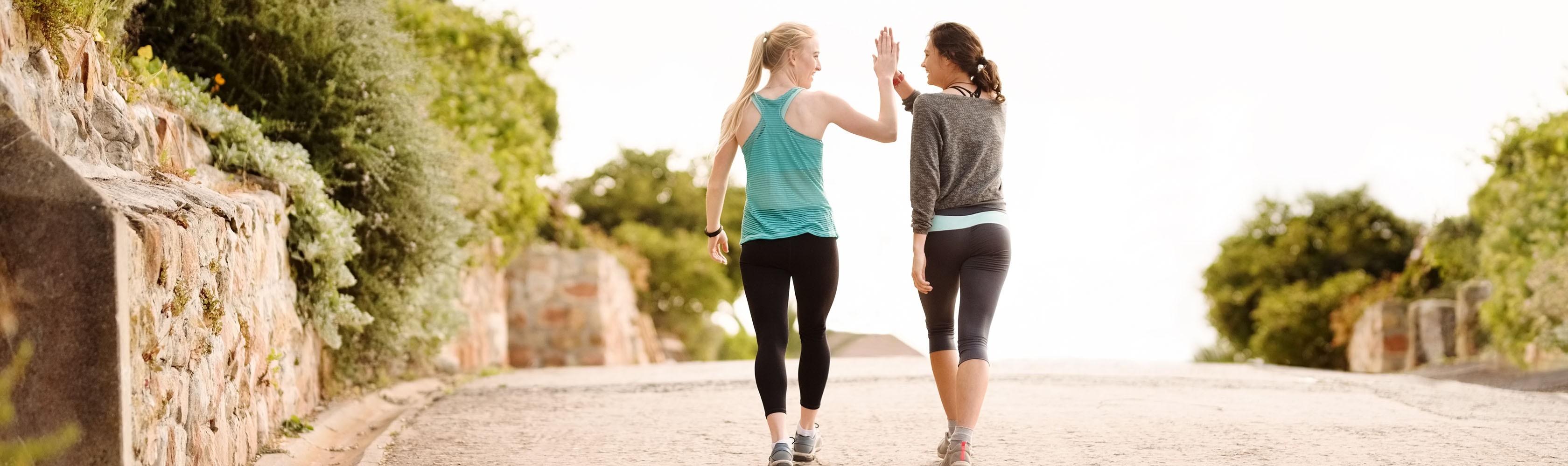 Zwei Freundinnen treffen sich zum Sport und klatschen sich zur Motivation gegenseitig ab