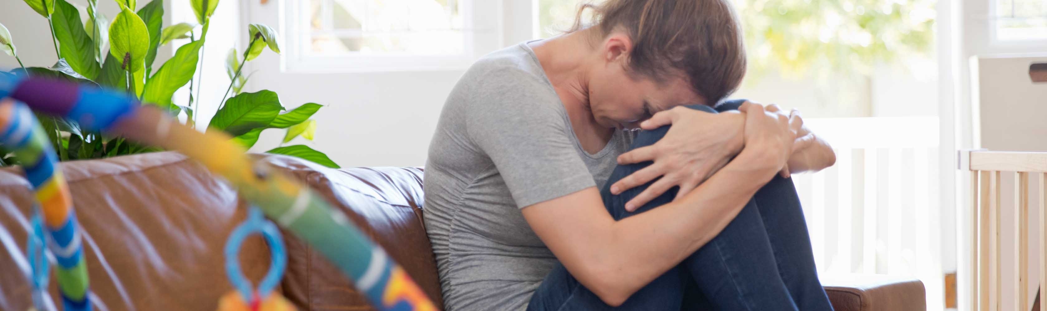 Geburtstrauma – Frau sitzt weinend auf dem Sofa.