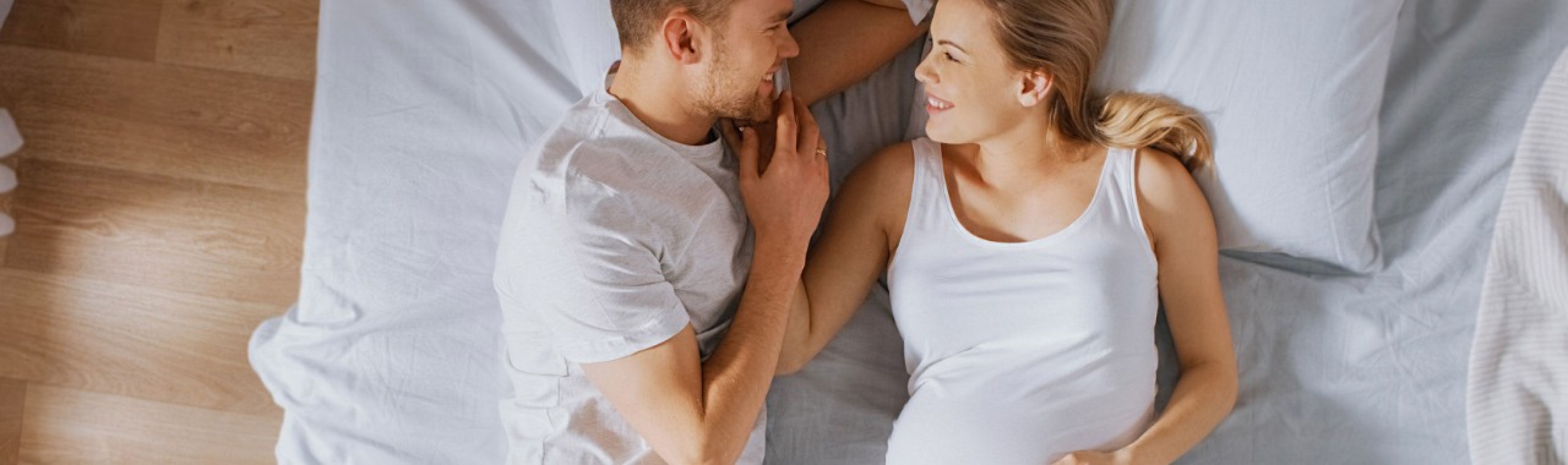 Partnerschaft und Sexualität nach der Geburt – Paar lächelt sich an, Frau ist schwanger