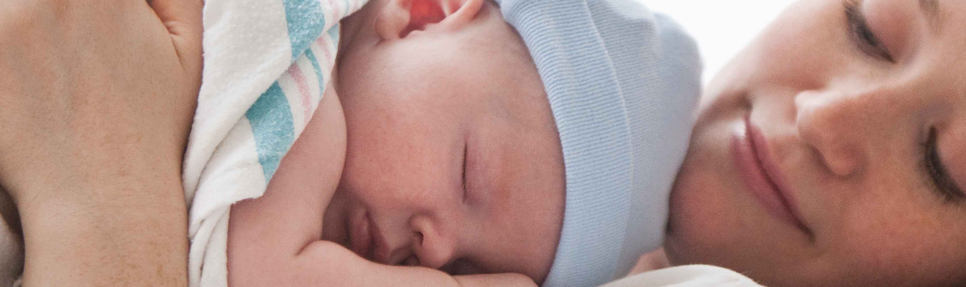 Unterstützung während des Wochenbetts - Mutter im Wochenbett mit neu geborenem Baby.