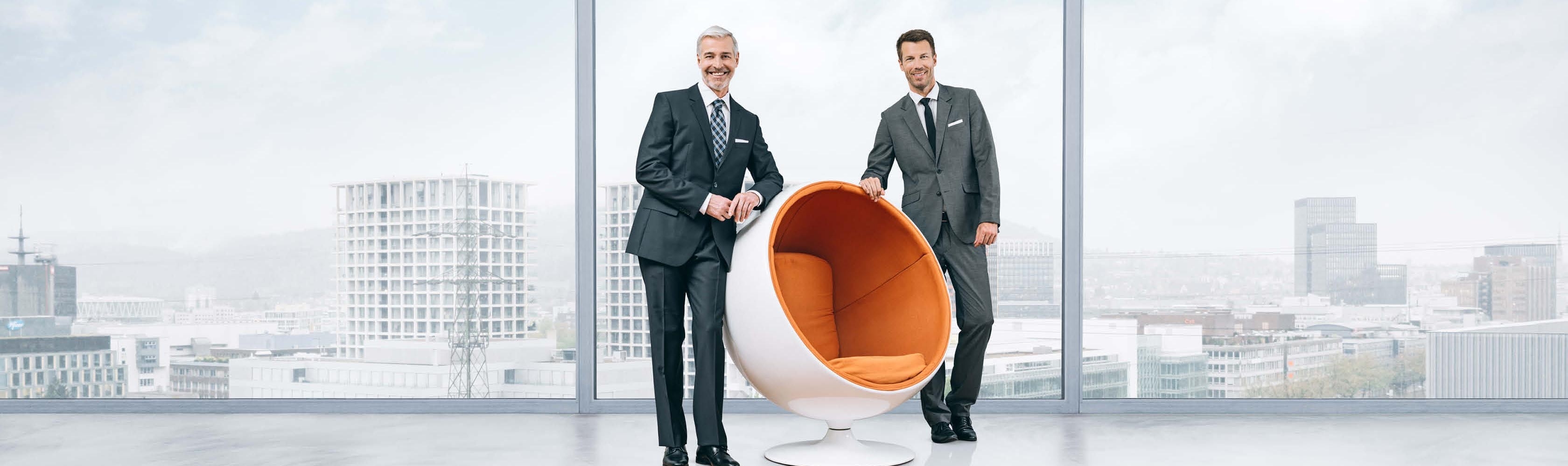 Männer stehen neben orangem Sessel