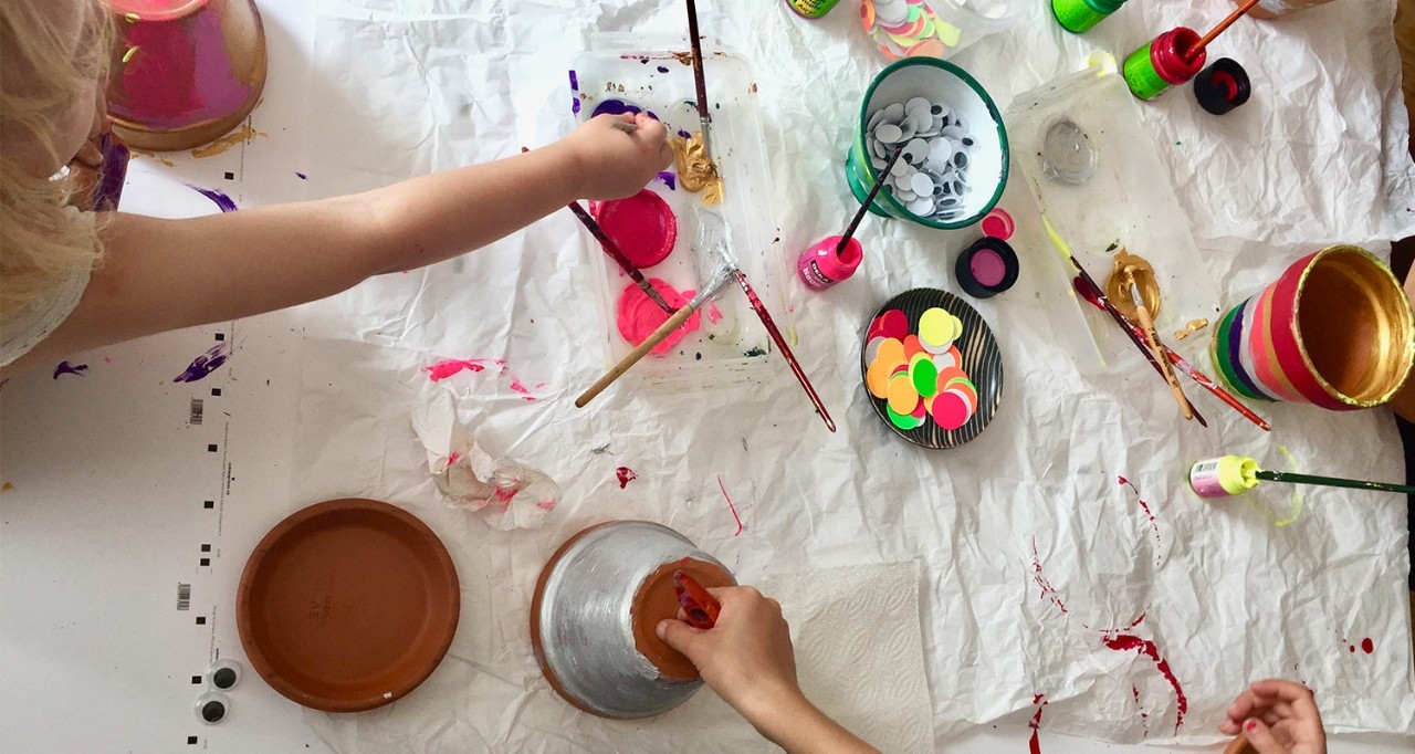 Des enfants peignent des pots de fleurs sur une table