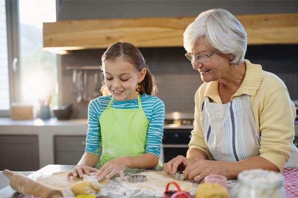 Une jeune fille prépare des biscuits avec sa grand-mère. Les traditions, recettes et remèdes se transmettent d’une génération à l’autre.
