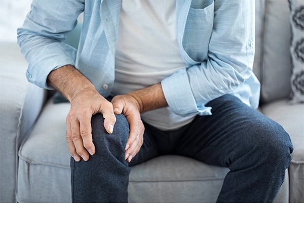 Douleurs au genou: un homme serre entre les mains son genou douloureux. Doit-il l’opérer ou non? Dans ce cas-là, solliciter un deuxième avis médical peut s’avérer très utile.