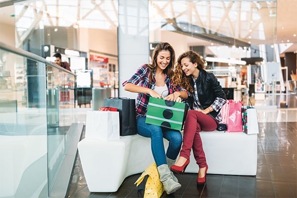 Deux adolescentes dans un centre commercial se réjouissent des merveilles qu’elles viennent d’acheter. Comment s’exerce la pression des marques.