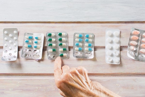 Plusieurs tablettes de comprimés et de gélules sont éparpillées sur une table. Lorsqu’une personne souffre de plusieurs maladies concomitantes, les traitements et les médicaments doivent être prescrits en tenant compte de son état de santé général. 