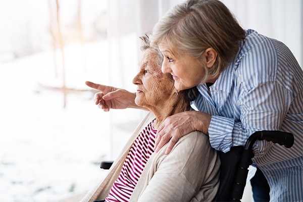 Besoin en soins après une chute. Une dame âgée et sa fille regardent par la fenêtre. Des offres de soutien sont proposées aux proches aidant·es. 