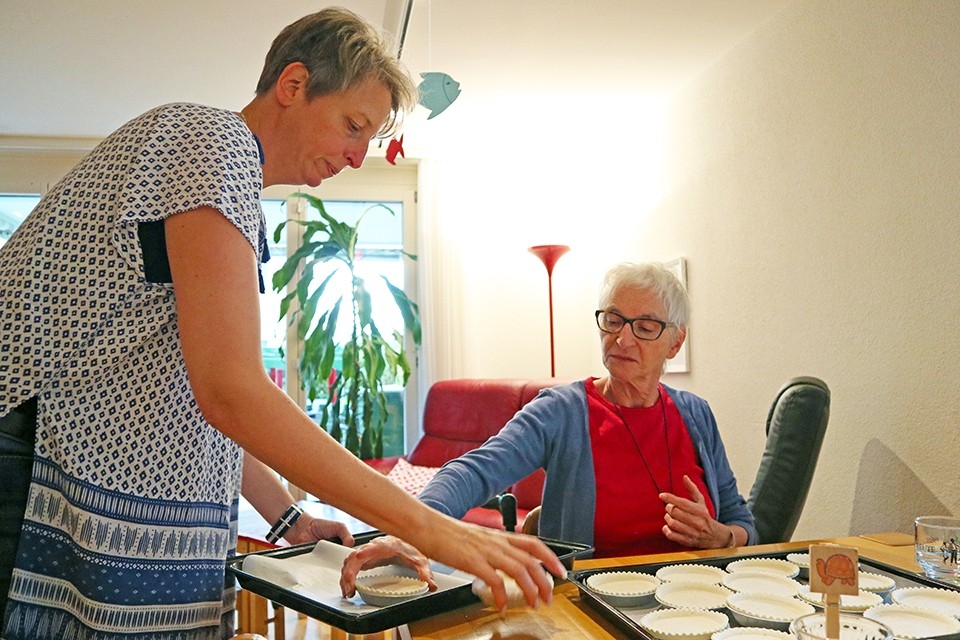 Une personne âgée prépare le dîner avec la directrice de la structure.