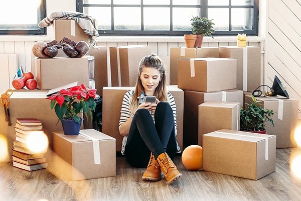 Pendant son déménagement, une jeune femme est assise devant ses affaires – bien emballées dans des cartons.