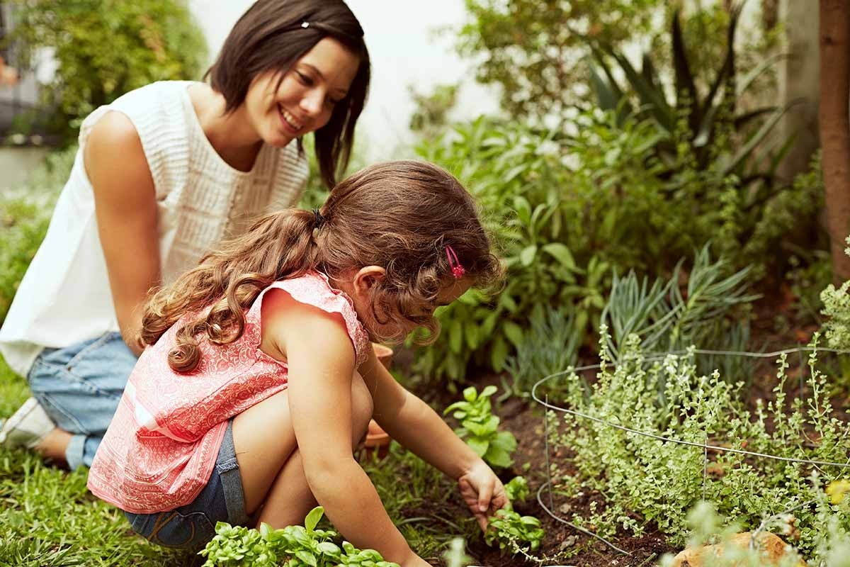 Une mère et son enfant sont dans le jardin. Les enfants imitent leurs parents et se constituent ainsi leur propre bagage cognitif.