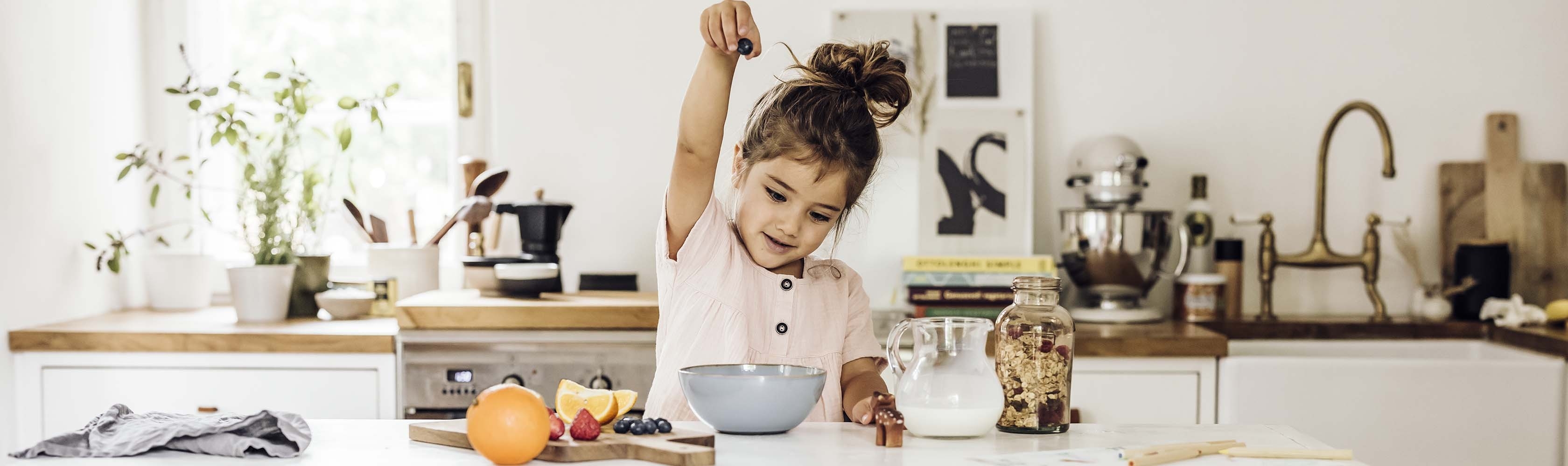 Mädchen in Küche macht sich ein Müesli