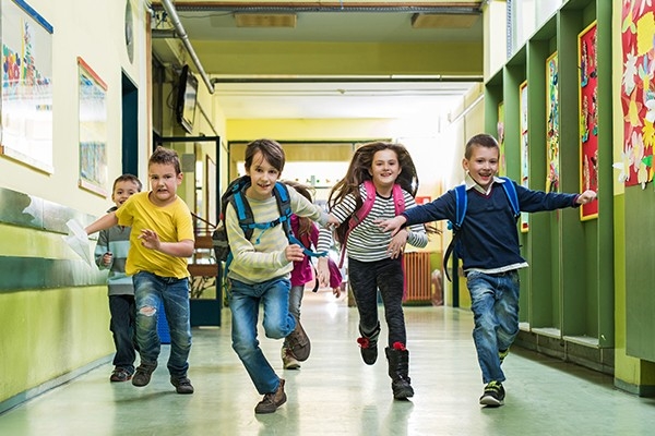 Ragazzini in corsa nell’atrio della scuola. La scuola in movimento è strutturata in modo da favorire le attività motorie.