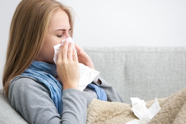 Una donna è sdraiata a letto con un raffreddore. Riposo e rimedi casalinghi provati sono a volte la migliore medicina per raffreddore e influenza.