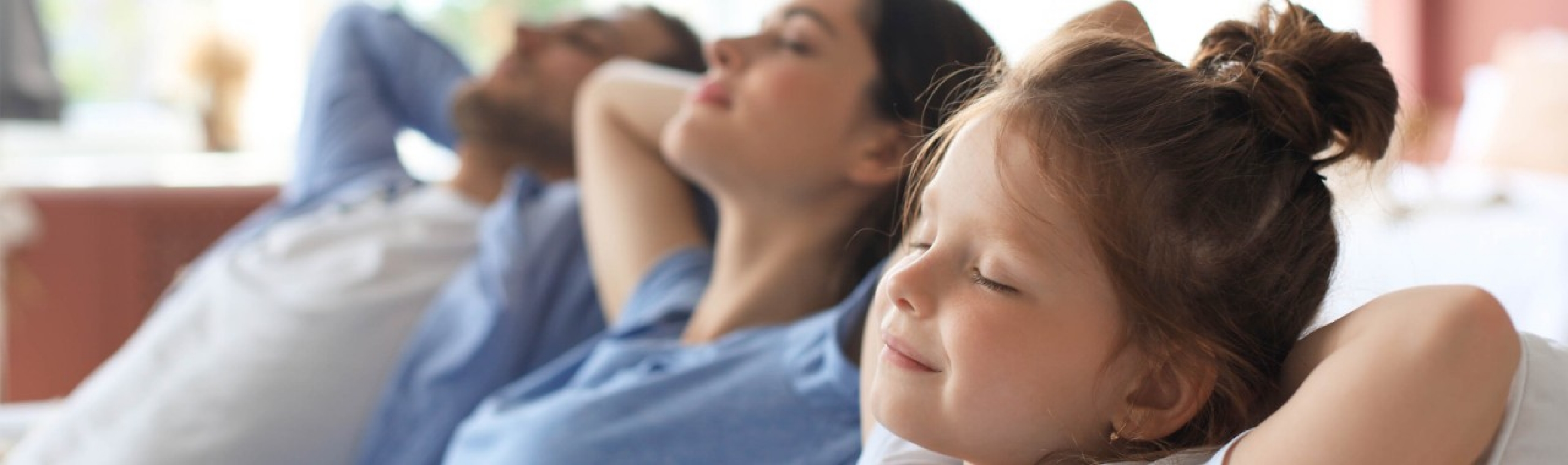 Più qualità di vita in famiglia: genitori e figlia si concedono insieme una pausa di relax sul divano.