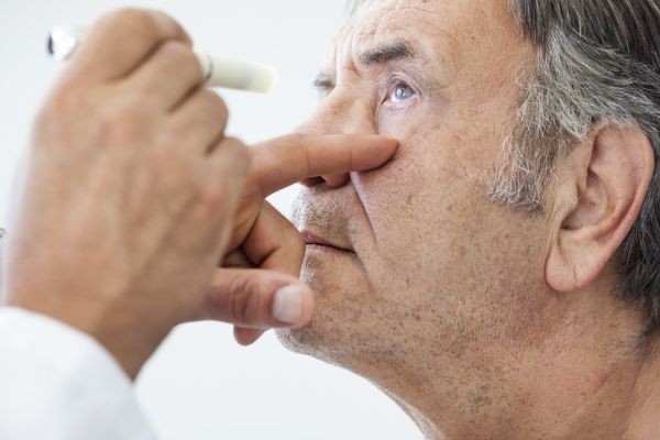 Diagnosi di cataratta: L'oculista esamina gli occhi di un uomo.