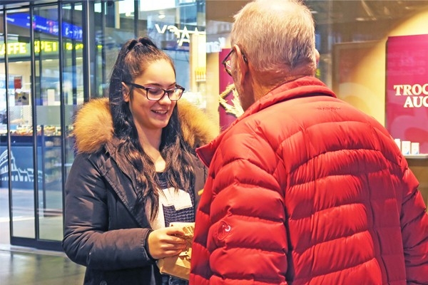 Impegno a favore della Festa dei lotta svizzera: una sorridente volontaria all’opera come venditrice dei spillette ESAF 2019 a Zugo.