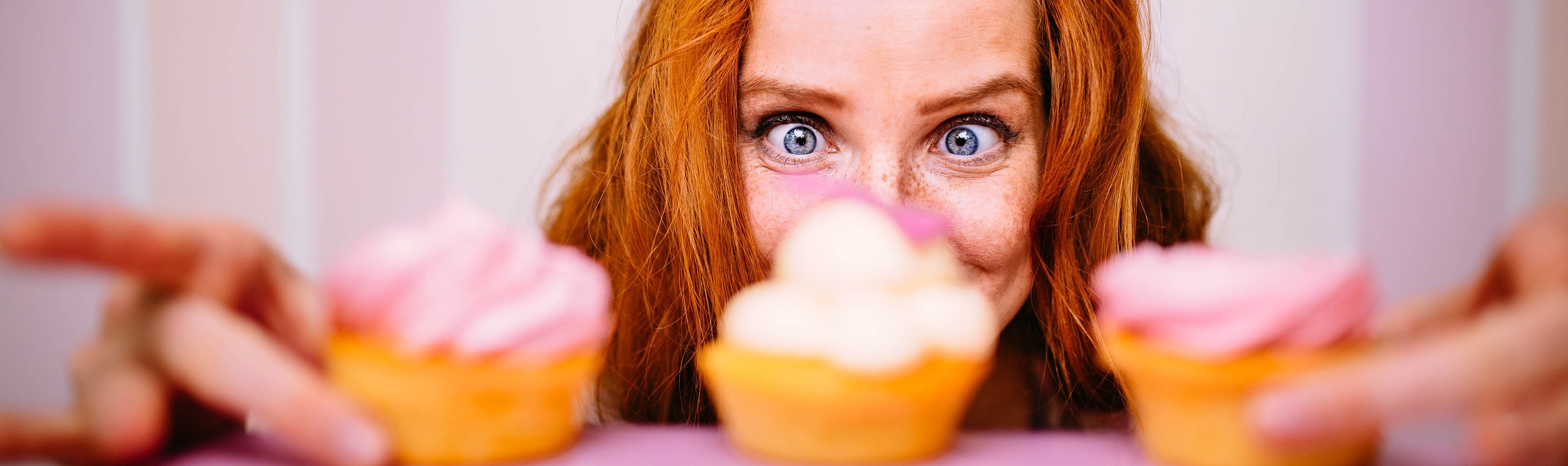Una donna ha tre cupcake davanti a sé e cerca di resistere al desiderio.