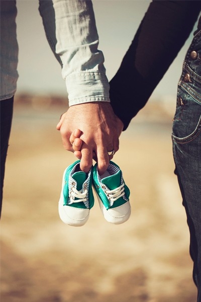 Una giovane coppia tiene in mano un paio di scarpette da neonato. Il loro desiderio di avere un figlio si è concretizzato. Siete forse in procinto di diventare genitori anche voi?
