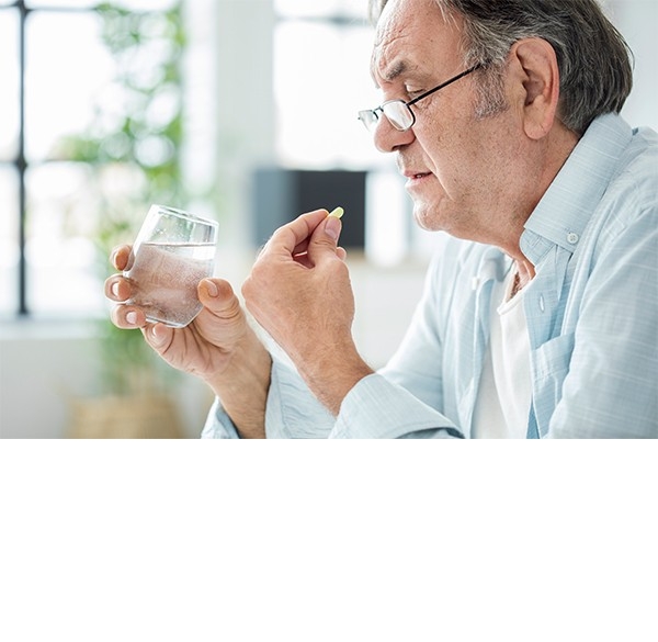 L'ABC dell'assunzione corretta dei medicamenti: un uomo tiene in mano un bicchiere di acqua e una pillola.