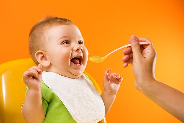 Un bebè, felice di mangiare la pappa.