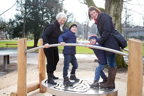 Generazioni in movimento senza frontiere. Due bambini, la loro mamma e la loro nonna esercitano l’equilibrio utilizzando assieme un’installazione di un parco progettato dalla fondazione Hopp-la.