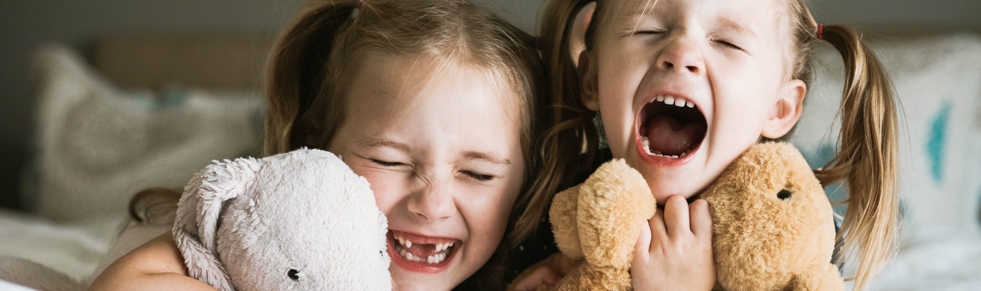Zwei Mädchen lachen zusammen. Ein Zahnversicherung lohnt sich, besonders für Kinder.
