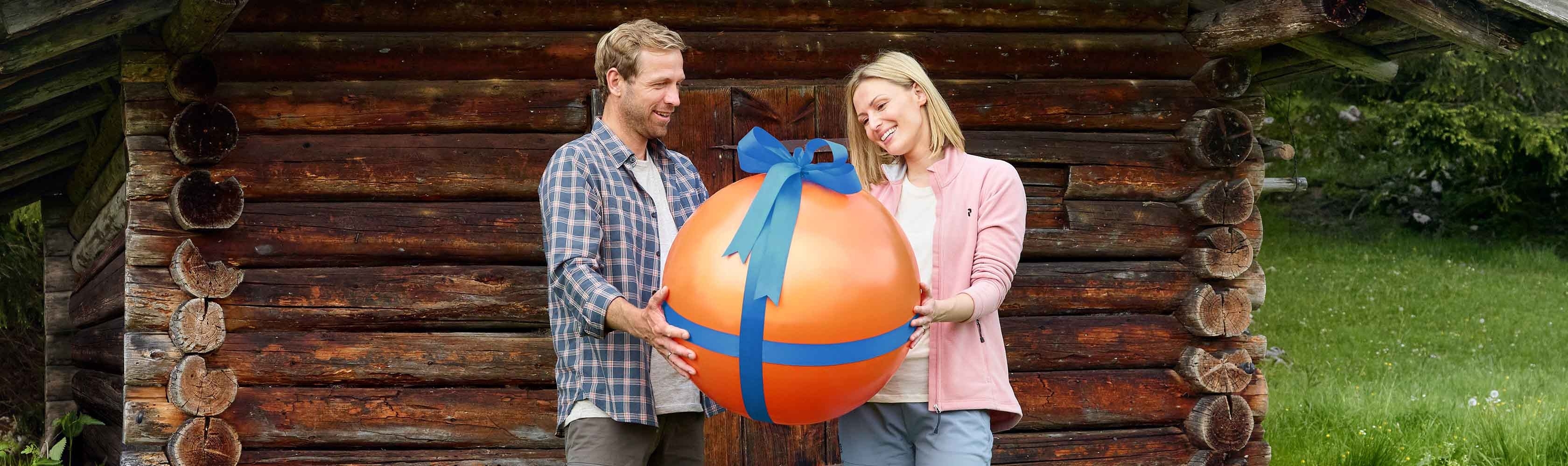Zwei Personen und einen orangen Ball als Geschenk verpackt.